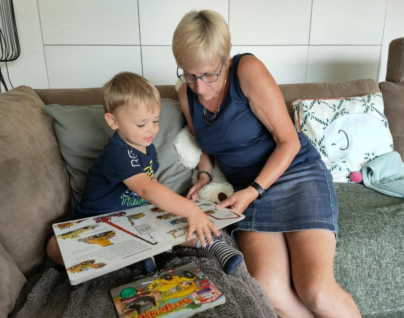 Dame leest boek met kindje in zetel
