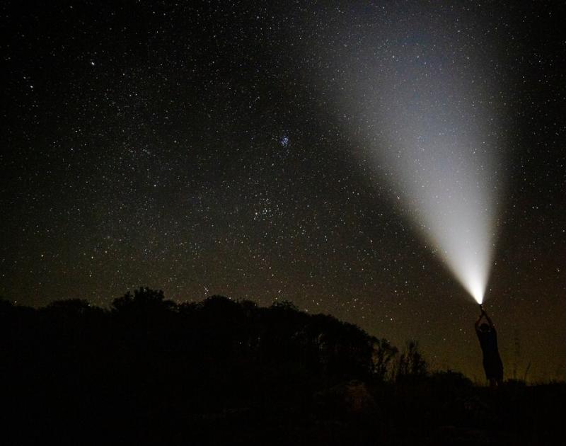 iemand schijnt met lamp naar sterrenhemel